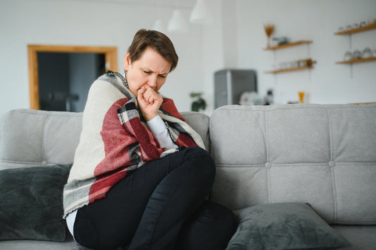 Femme congelée malade des années 50 assise sur un canapé dans un salon couvert d'éternuements chauds de plaid, le nez rassis se sent malsain, froid de saison, concept du système immunitaire affaibli